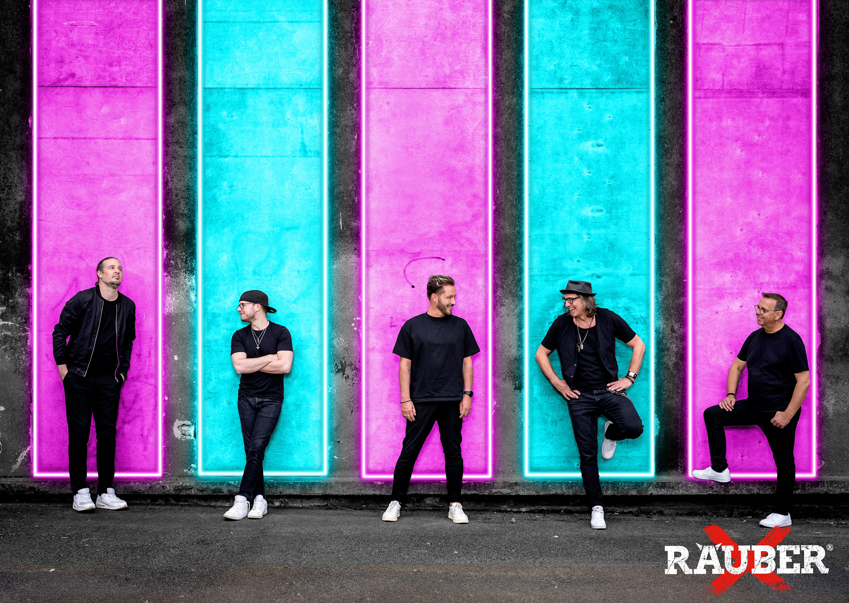 Band Räuber vor bunter Neonwand, fünf Mitglieder in schwarzer Kleidung, Promoaufnahme 2025